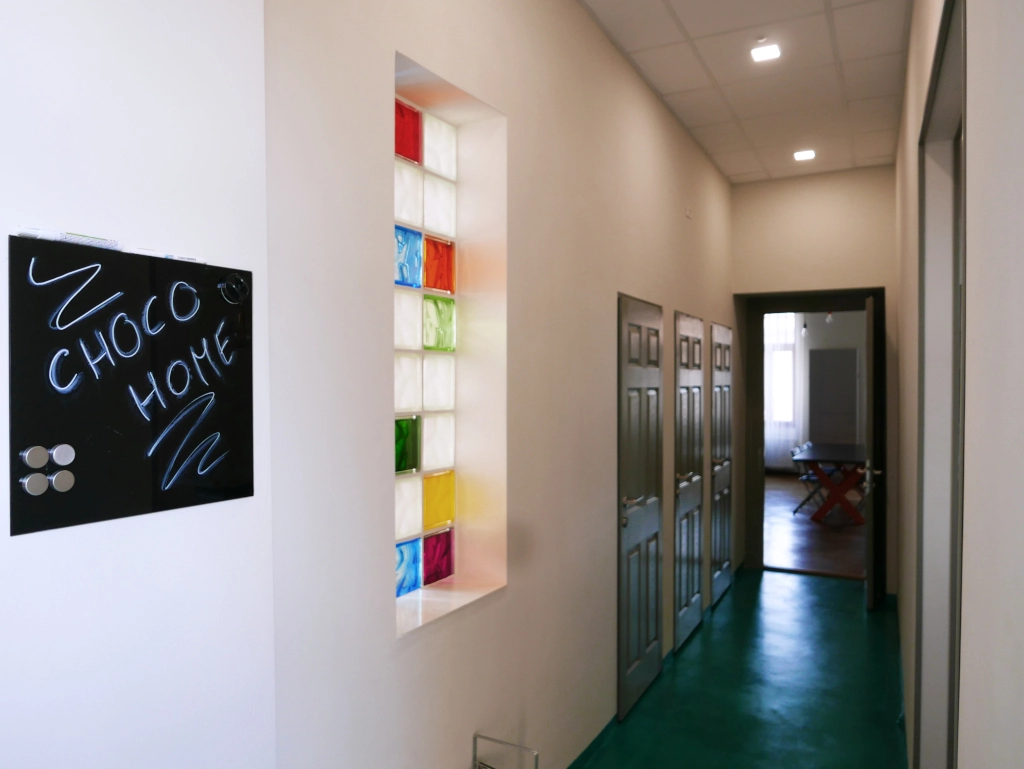 Brightly lit interior hallway with modern colorful glass block accents at Choco Home and Hostel.