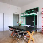 Spacious 8-bed mixed dormitory room with bunk beds, personal lockers, and a central group table.