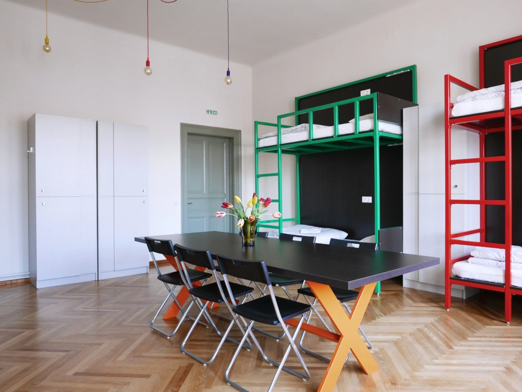 Spacious 8-bed mixed dormitory room with bunk beds, personal lockers, and a central group table.